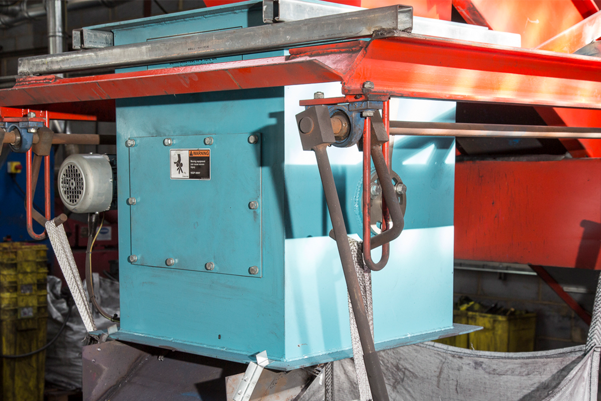 Housed drum magnet beneath red processing-line steelwork